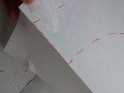 Fold mønster papiret i skulderlinjen på nakkebelægningen. Du skal ikke klippe mønsterdelen ud endnu, for du skal tegne mere på papiret.